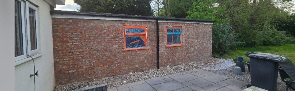 Single-storey side wall stripped back to brick with window frames masked